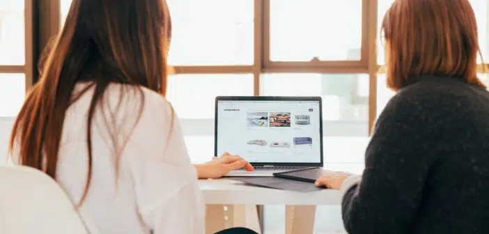 two women talking while looking at laptop computer